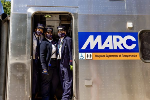 MARC train conductors smile under their masks as they operate the shuttle transporting guests from Baltimore Penn Station to the event site.