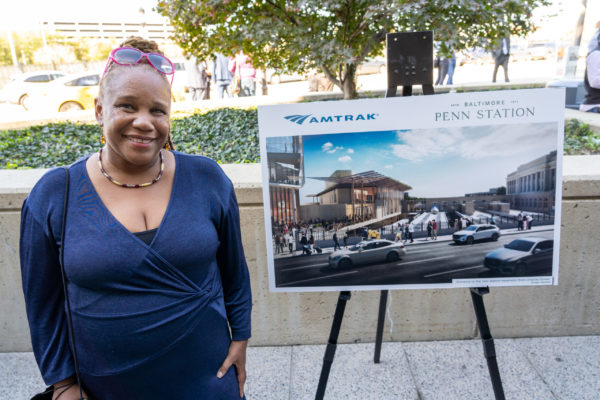 Lauren Kelly-Washington stands next to a new rendering of Baltimore Penn Station.