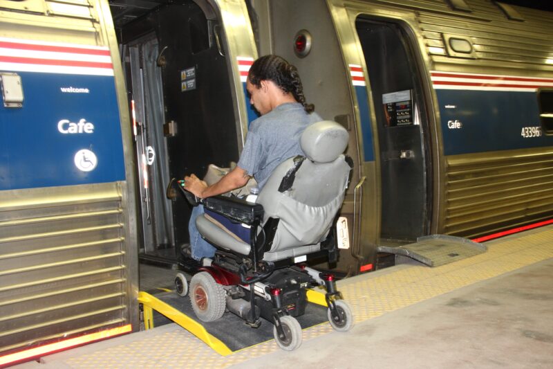 Passenger boards train with wheeled mobility device.