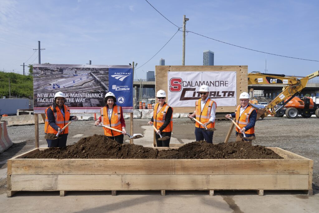 Amtrak and partners post for a groundbreaking photo with dirt on shovels at Sunnyside Rail Yard